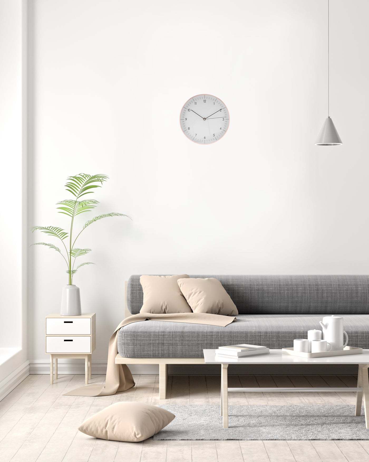 Große Wanduhr in weiss und rosegold hängt im Wohnzimmer über grauer Couch und Beistelltisch mit Vase 