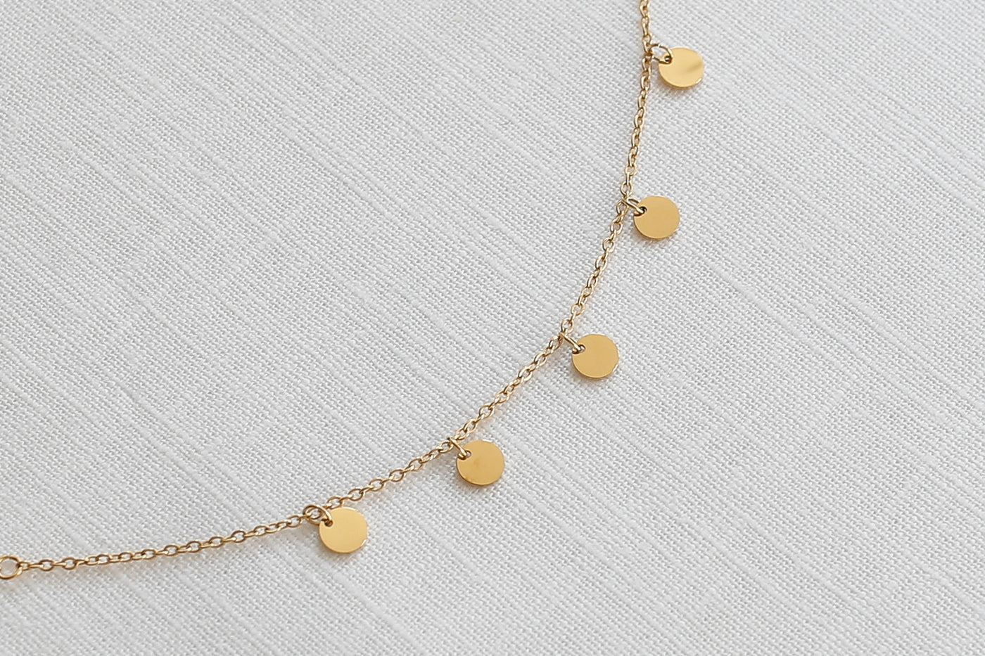 Gold Farbenes Plättchen Armband mit verstellbarem Verschluss im minimalistischen Stil auf einem Stoff Tuch 