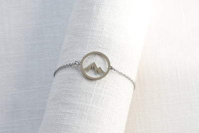 Filigranes Armband mit Bergspitze Anhänger in Silber auf weißem Leinen Tuch.