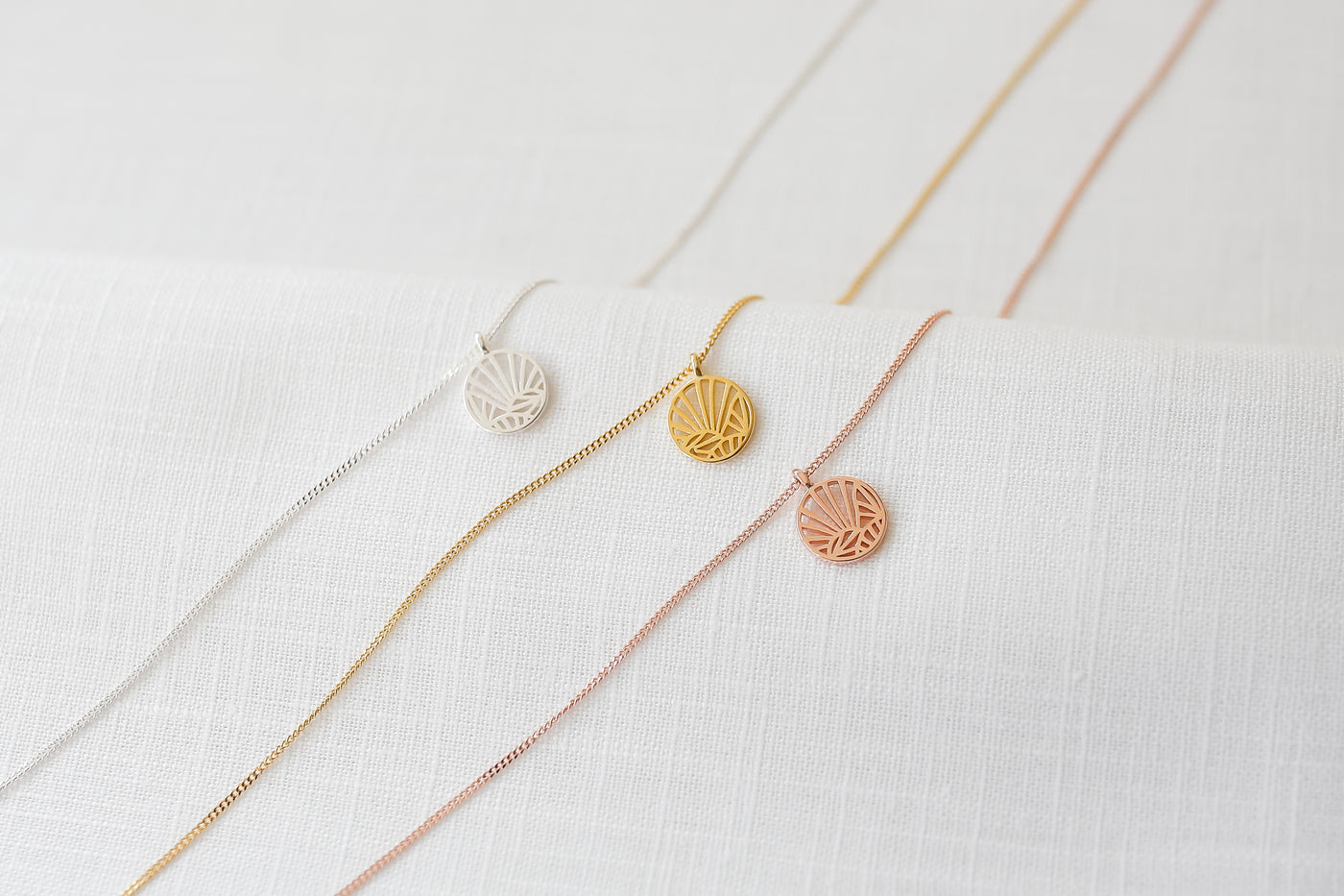 Drei alltagstaugliche Halsketten mit abstraktem Grid Anhänger in jeweils Silber, Gold und Rosegold auf Stoff 