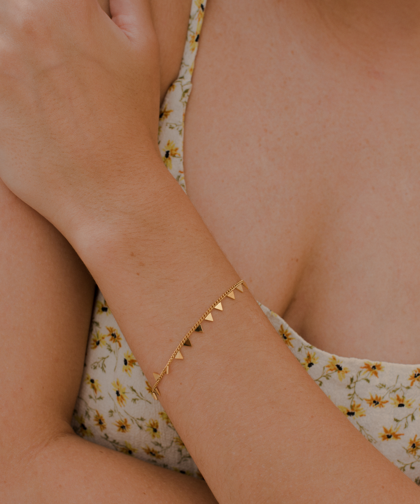 Junge Frau trägt Gold Armband mit minimalistischem Dreieck Plättchen Anhänger.