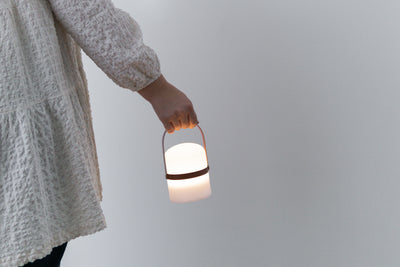 Frau hält moderne kleine LED Laterne am Holz Griff in Terrakotta