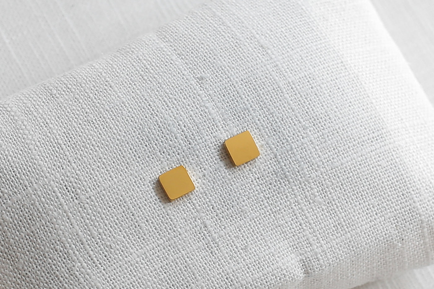 Quadratische Ohrstecker in Gold aus Edelstahl auf Stoff