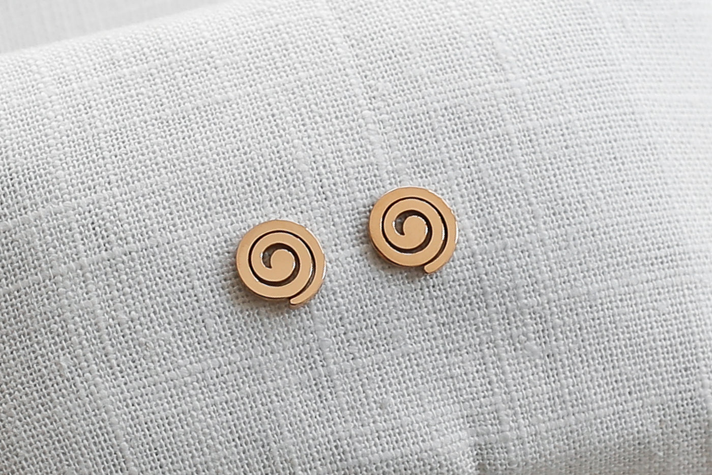 Rosa farbene Ohrringe mit Spiralen Stecker auf Stoff