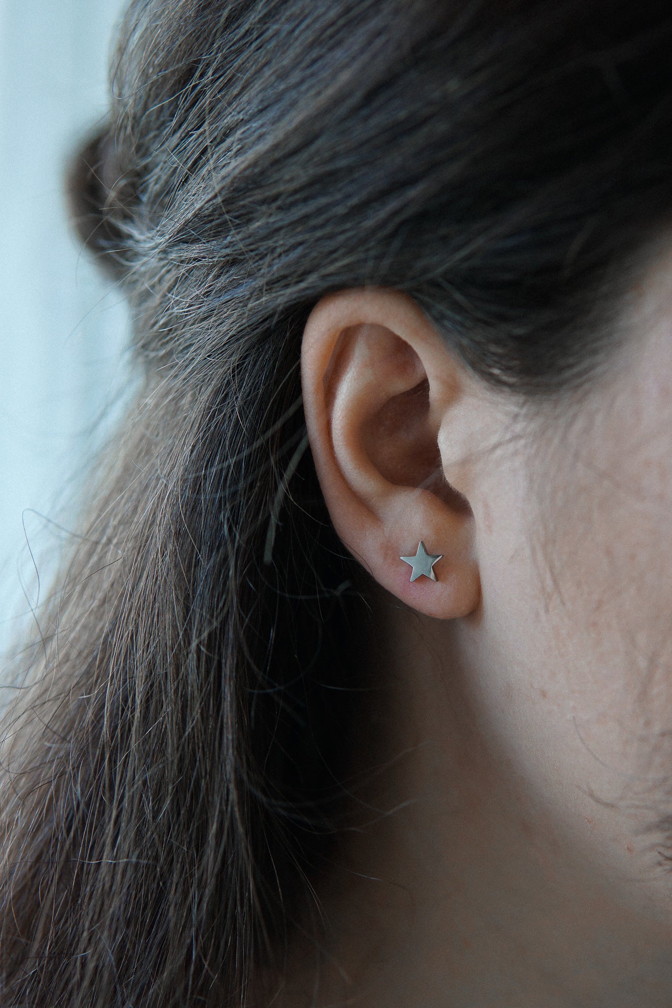 Junge Dame trägt silberne Stern Ohrstecker aus Edelstahl 