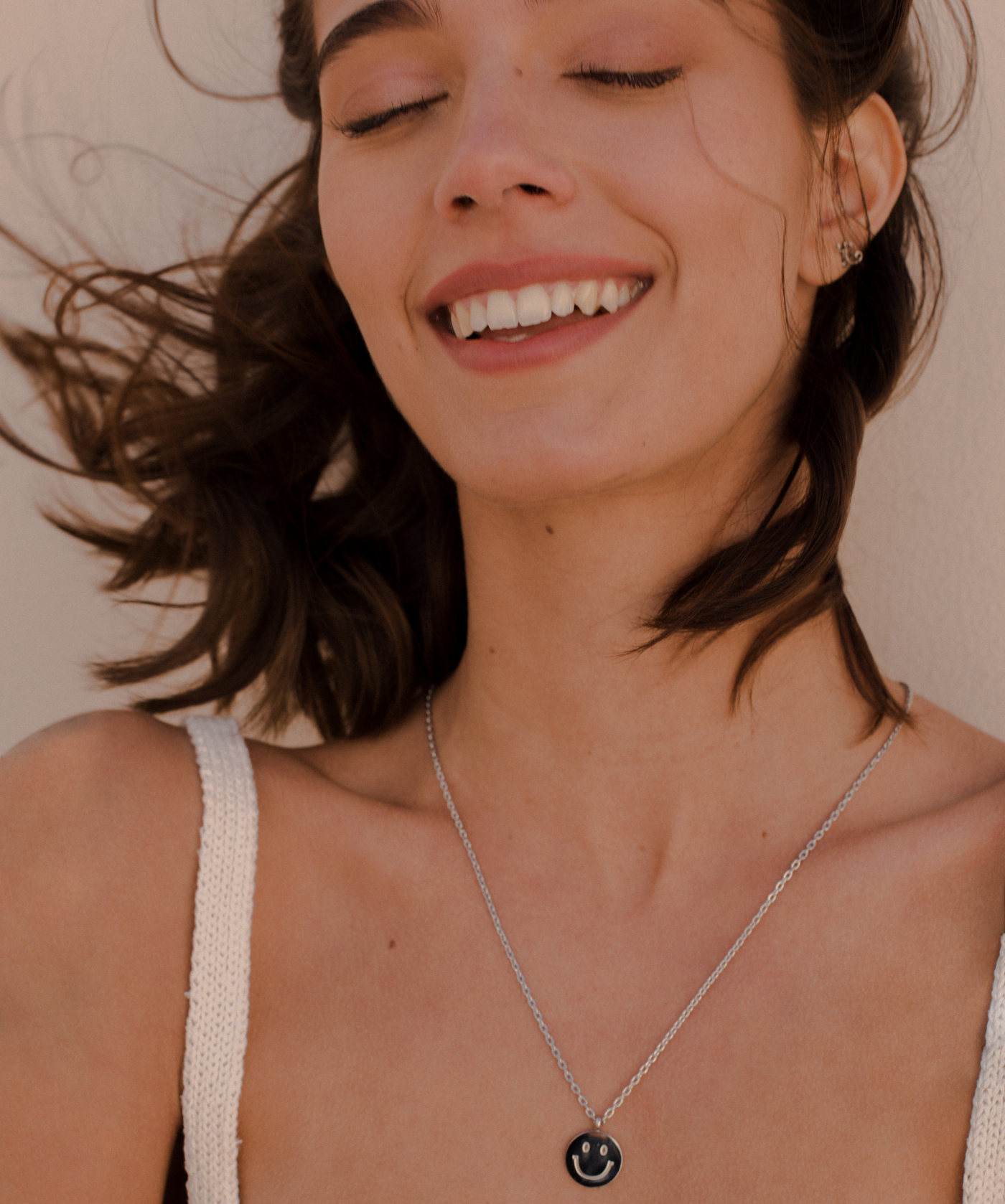Glückliche Frau trägt minimalistische Halskette mit Smiley Anhänger aus Edelstahl.