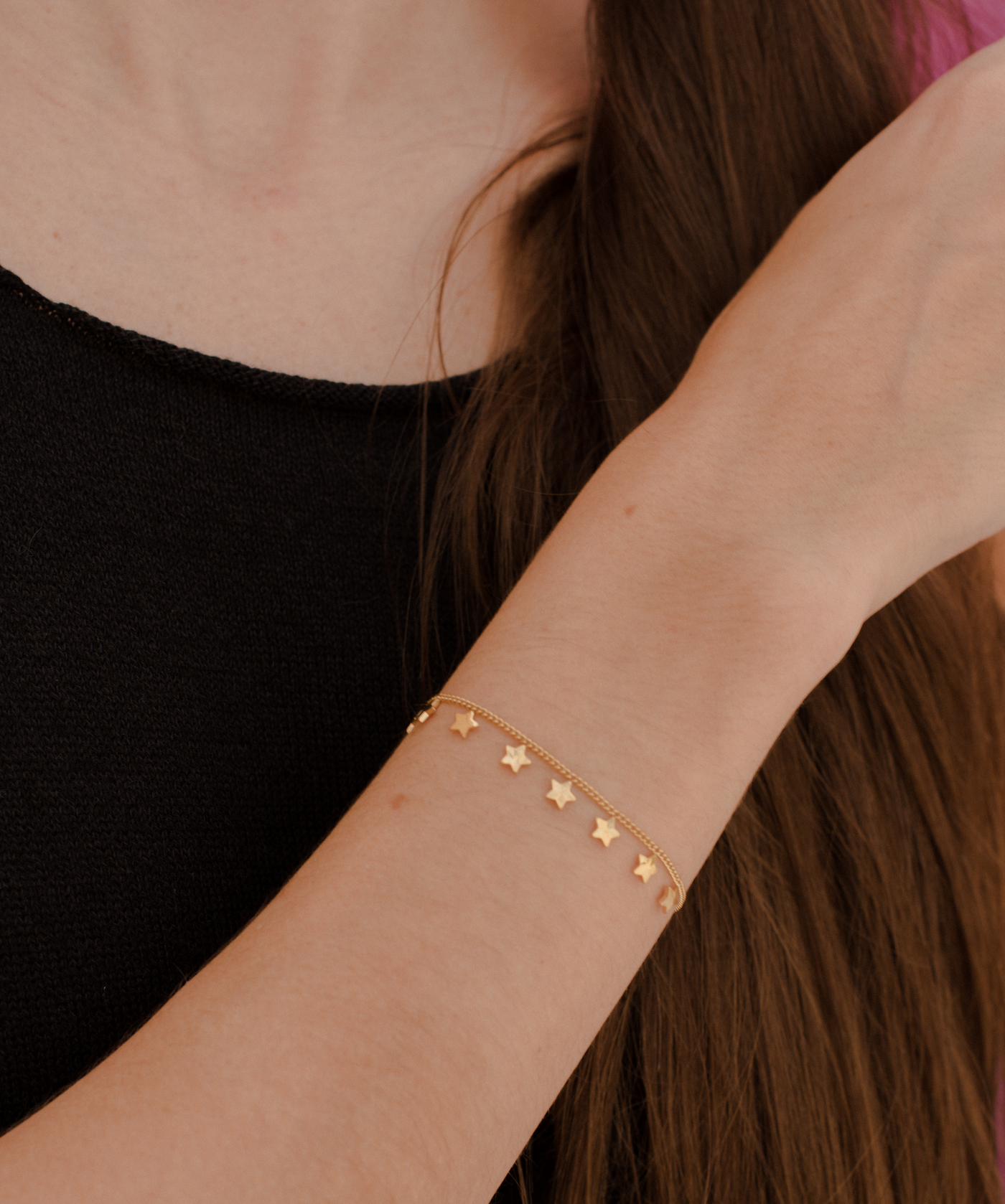 Frau trägt vergoldetes Armband aus Edelstahl mit kleinen Stern Anhängern 