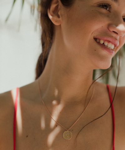 Lachende Frau trägt Rose farbene Kette mit Mandala Motiv 