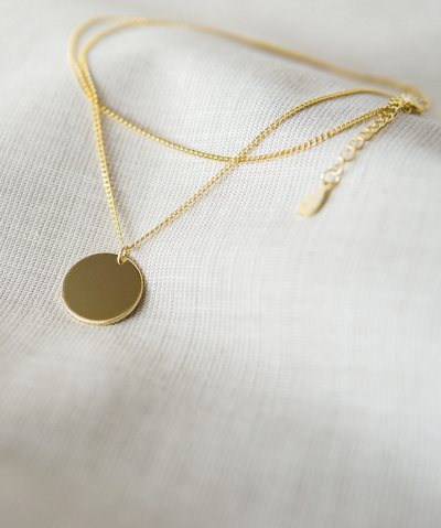 Gold Farbene Plättchen Halskette mit verstellbarem Verschluss im minimalistischen Stil auf einem Stoff Tuch 
