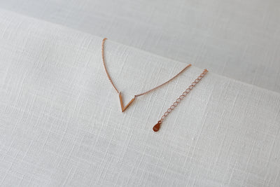 Rose farbene Halskette mit V Anhänger im Boho Stil auf Leinen Stoff