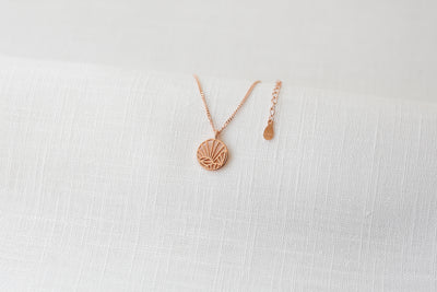 Rosegoldene Kette mit Motiv Anhänger und verstellbarem Verschluss auf Stoff