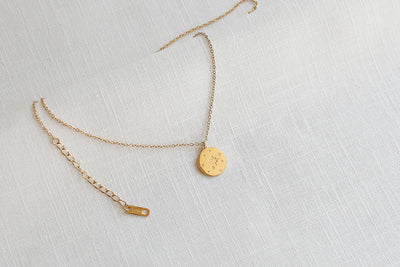 Kette mit Sternenhimmel Anhänger und verstellbarer Länge in Gold platziert auf Leinen Stoff.