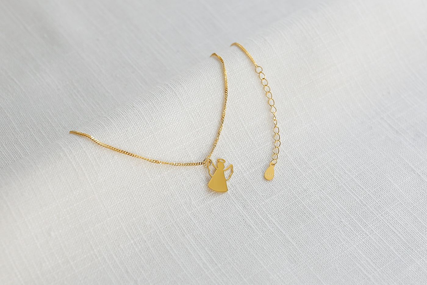 Feminine Halskette mit Engel Anhänger in Gold auf einem Stoff Tuch 
