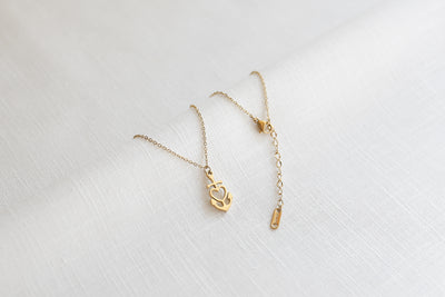Goldene Halskette platziert auf Leinen Stoff mit Herz-Anker Symbol und verstellbarem Verschluss