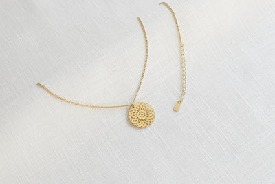 Hautverträgliche Gold Kette mit Mandala Anhänger und Einhakverschluss auf Stoff