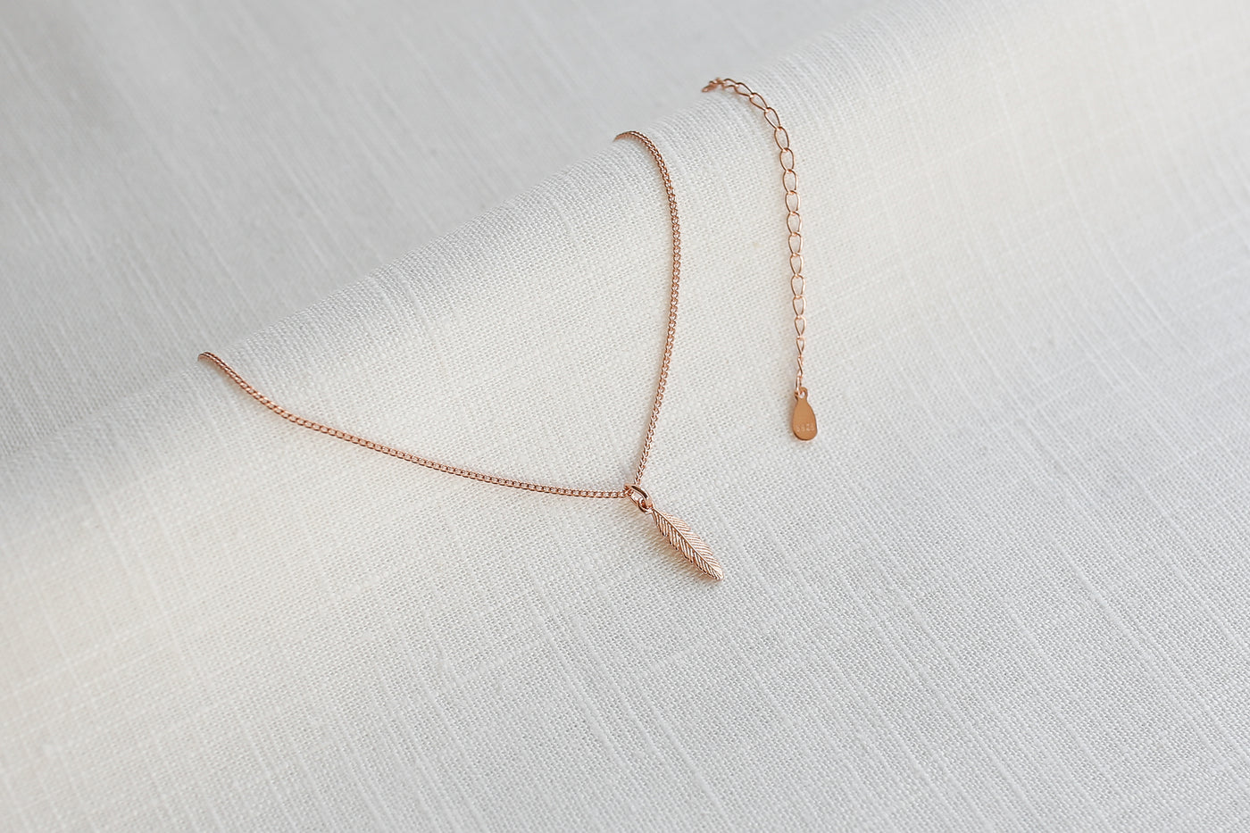 Verstellbare Kette mit Feder Anhänger in Rosegold auf Leinen Stoff