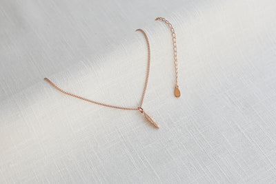 Verstellbare Kette mit Feder Anhänger in Rosegold auf Leinen Stoff