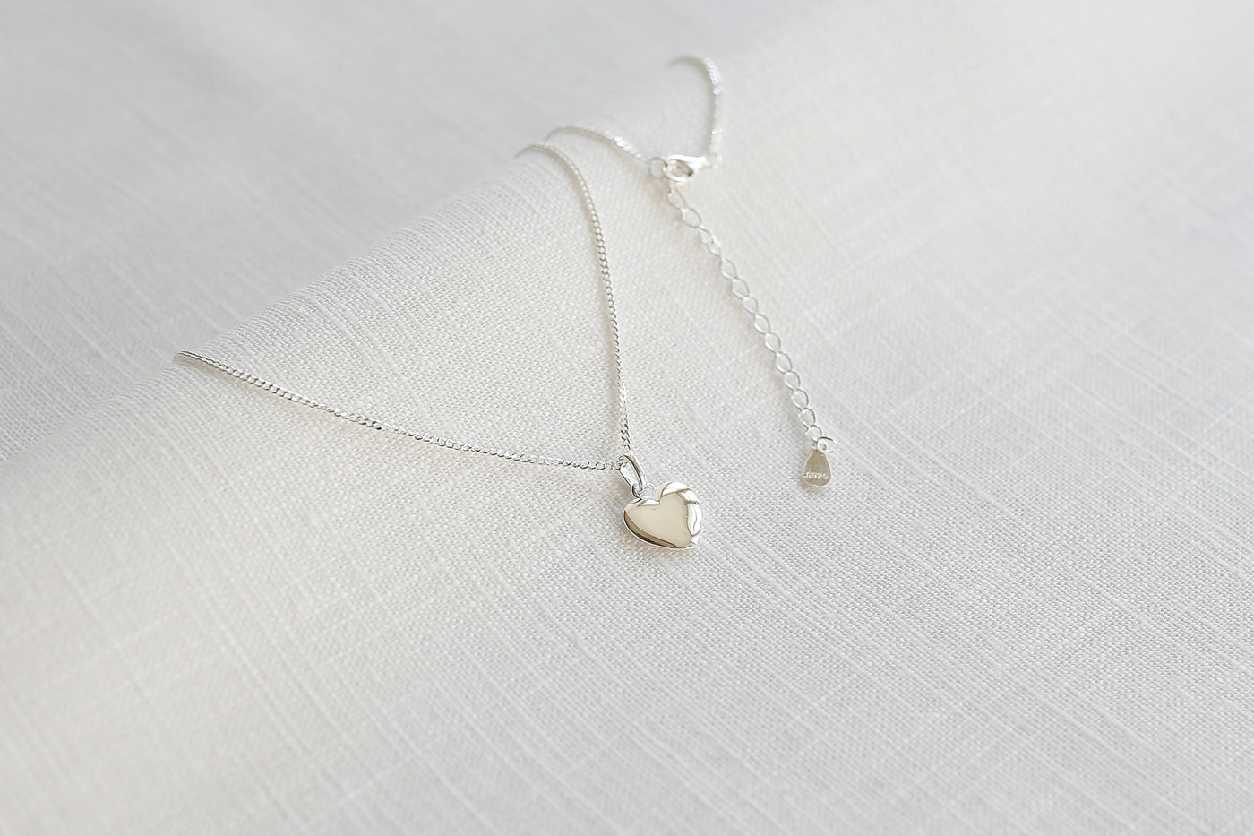 Silber Kette mit Herz Anhänger und verstellbarem Verlängerungsverschluss auf Stoff 