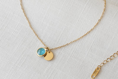 Goldene Halskette mit blauem Stein Anhänger platziert auf Leinen Stoff