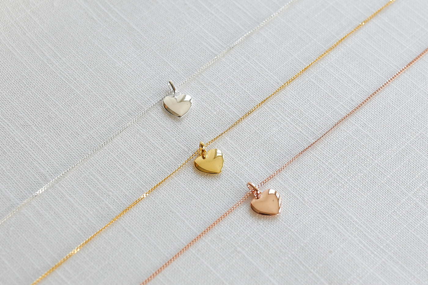 Drei alltagstaugliche Halsketten mit Herz Anhänger in jeweils Silber, Gold und Roségold auf Stoff