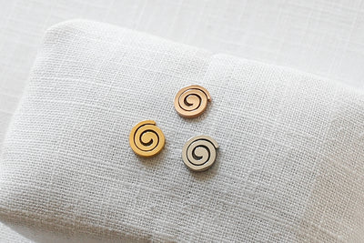 Drei unterschiedlich farbige Ohrringe mit Spiralen Motiv in jeweils Gold, Silber und Rosegold 