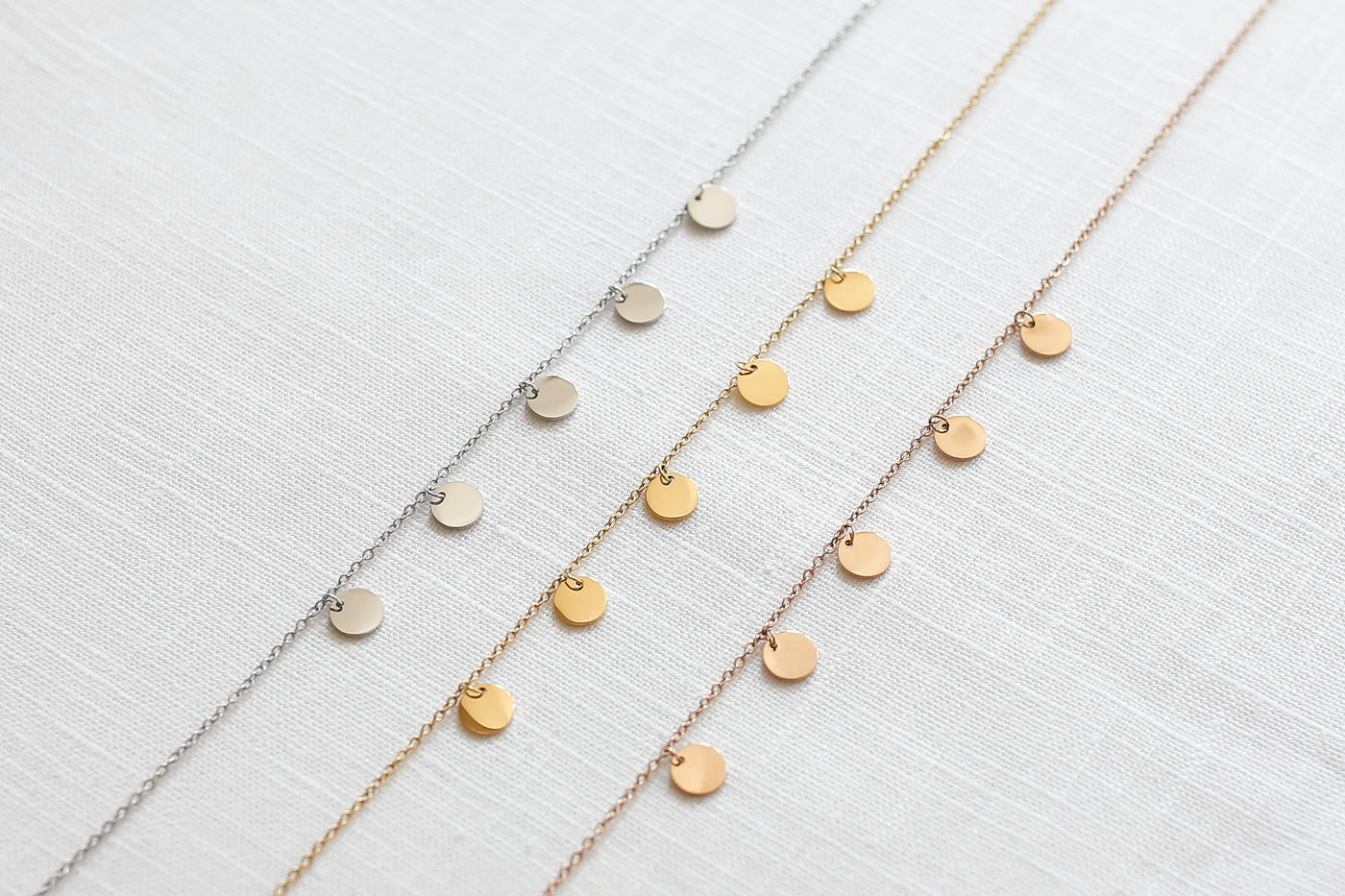 Drei verstellbare Halsketten mit Plättchen Anhänger in den Farben Silber, Gold und Roségold aus Edelstahl auf Stoff 