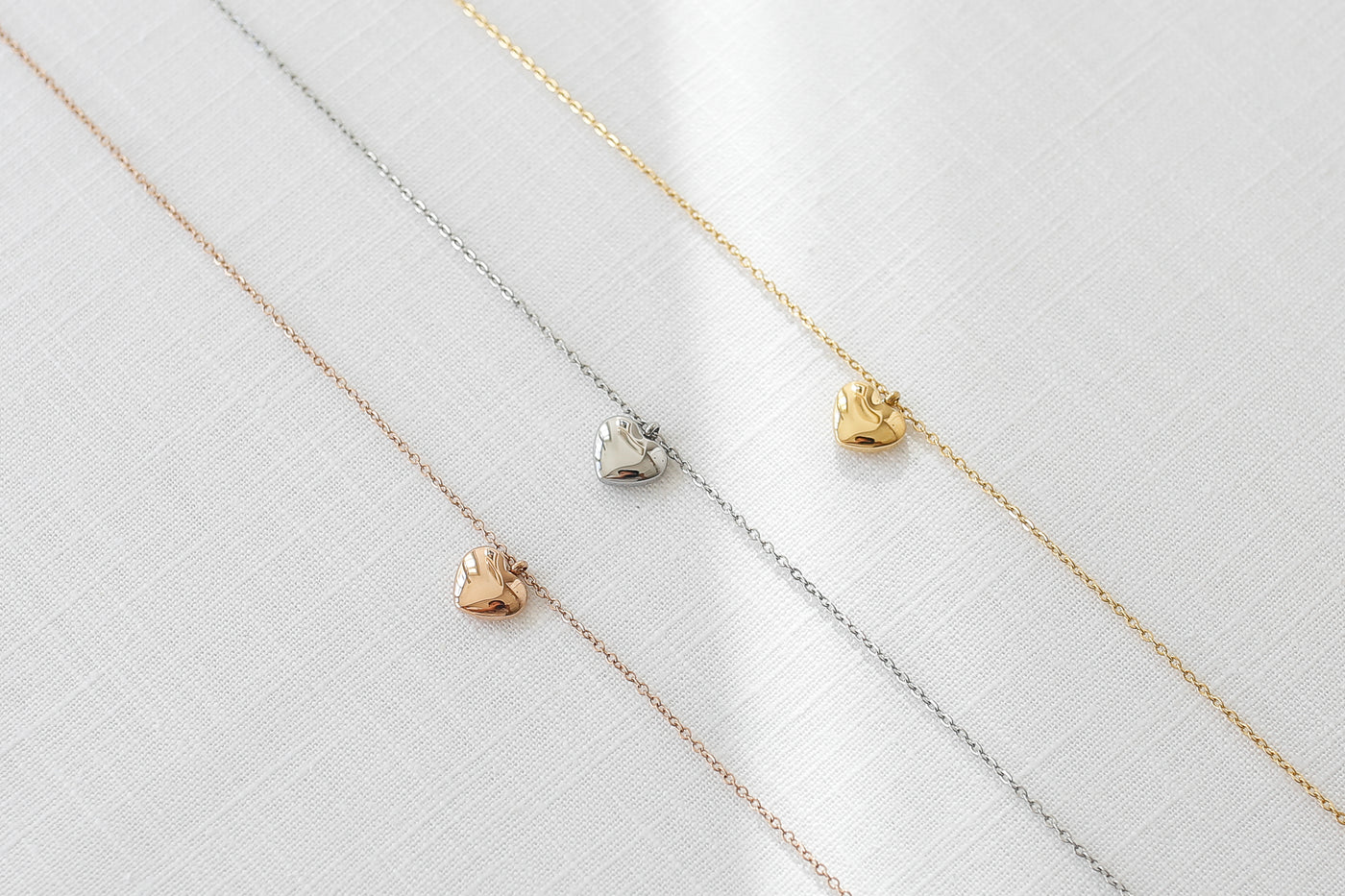 Drei alltagstaugliche Halsketten mit Herz Anhänger in jeweils Silber, Gold und Rosegold auf Stoff