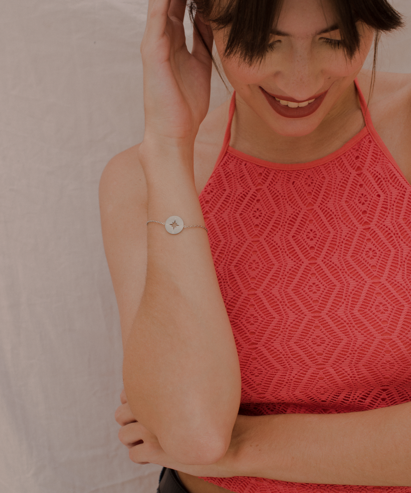 Glückliche Frau trägt minimalistisches Armband mit Kompass Anhänger und eleganten verzierungen
