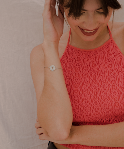 Glückliche Frau trägt minimalistisches Armband mit Kompass Anhänger und eleganten verzierungen