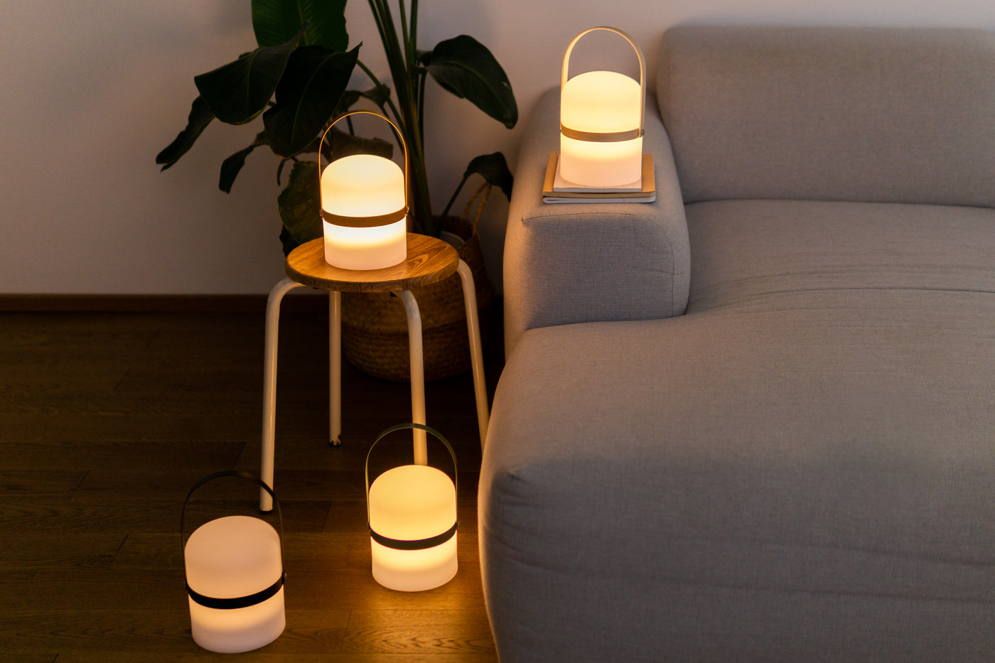 Vier schlichte Campinglichter mit unterschiedlich farbigen Holz Henkeln im Wohnzimmer