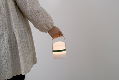 Dame hält moderne LED Laterne in klein am grünem Holz Griff 