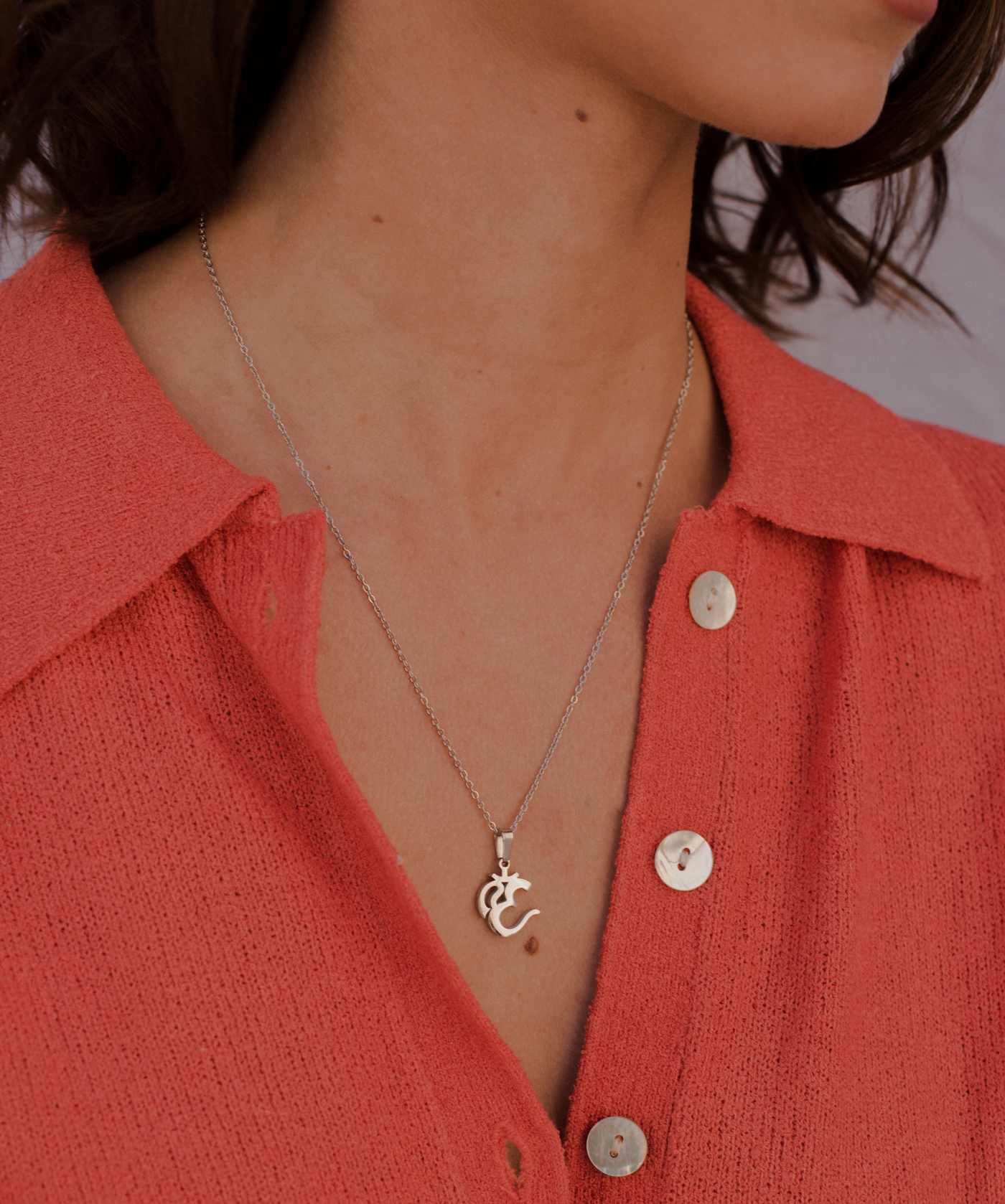 Glückliche Frau trägt minimalistische Halskette mit Om Anhänger aus Edelstahl.