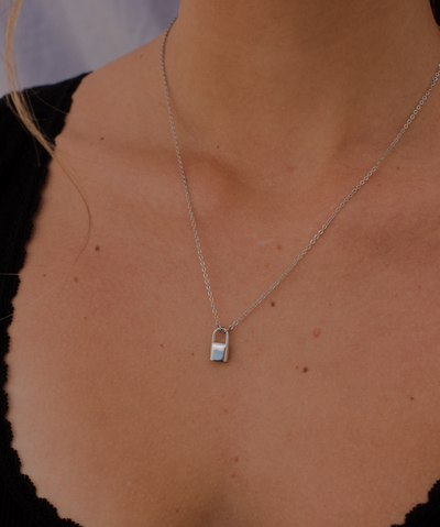 Frau trägt minimalistische Halskette mit Schloss Anhänger aus Edelstahl in Silber