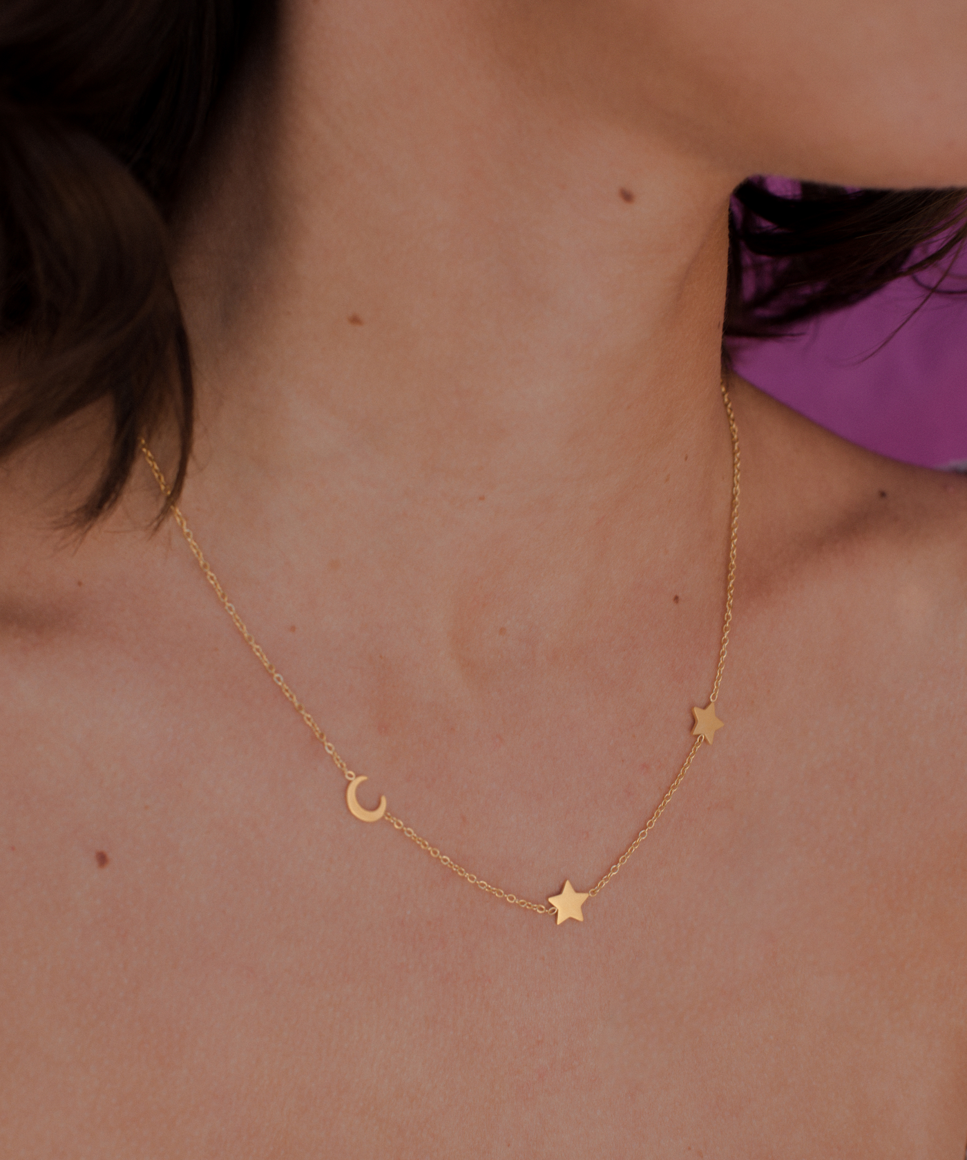 Junge Frau trägt Gold Kette mit minimalistischem Mond und Stern Anhänger.