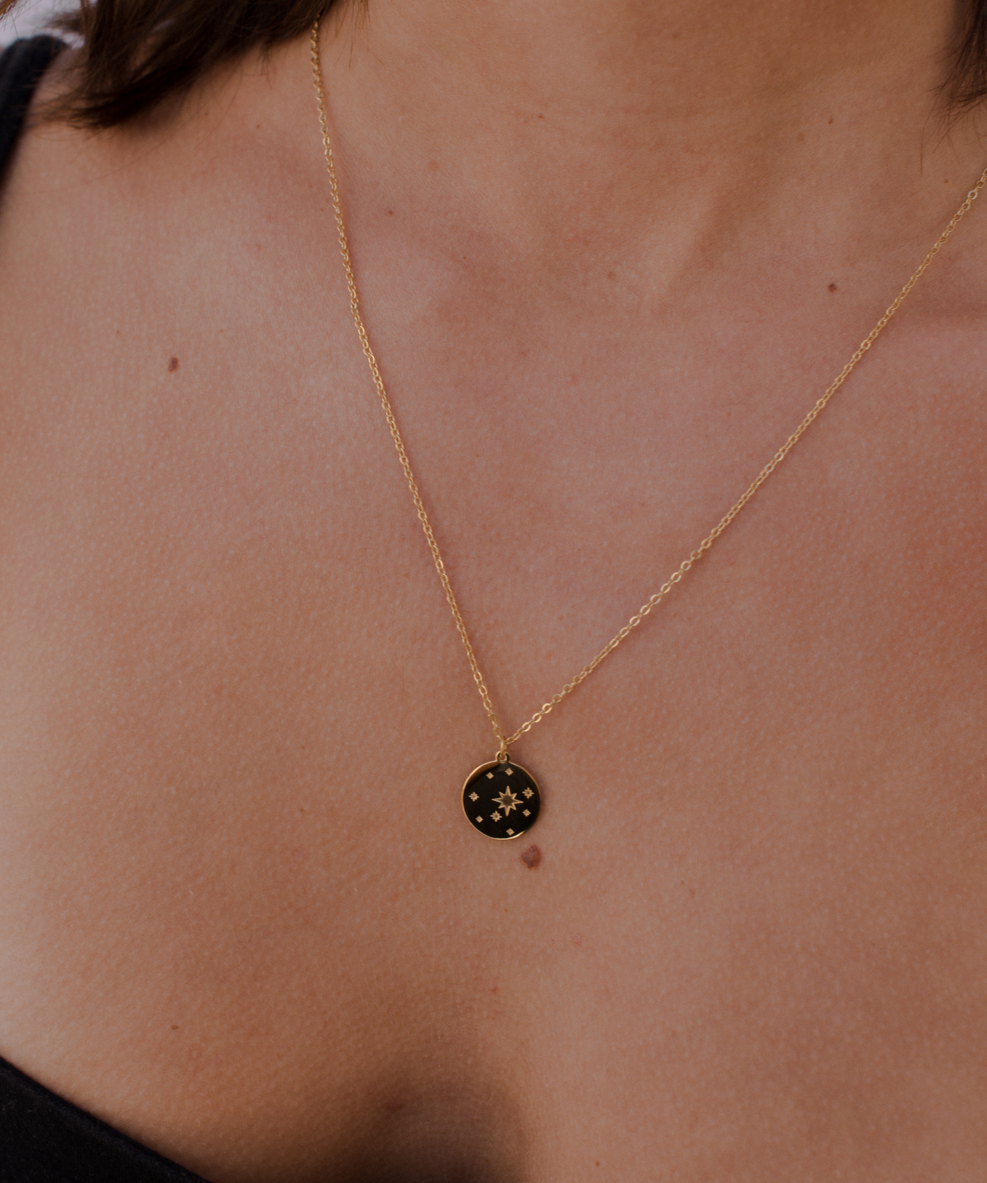 Junge Frau trägt Gold Kette mit minimalistischem Sternenhimmel Anhänger.