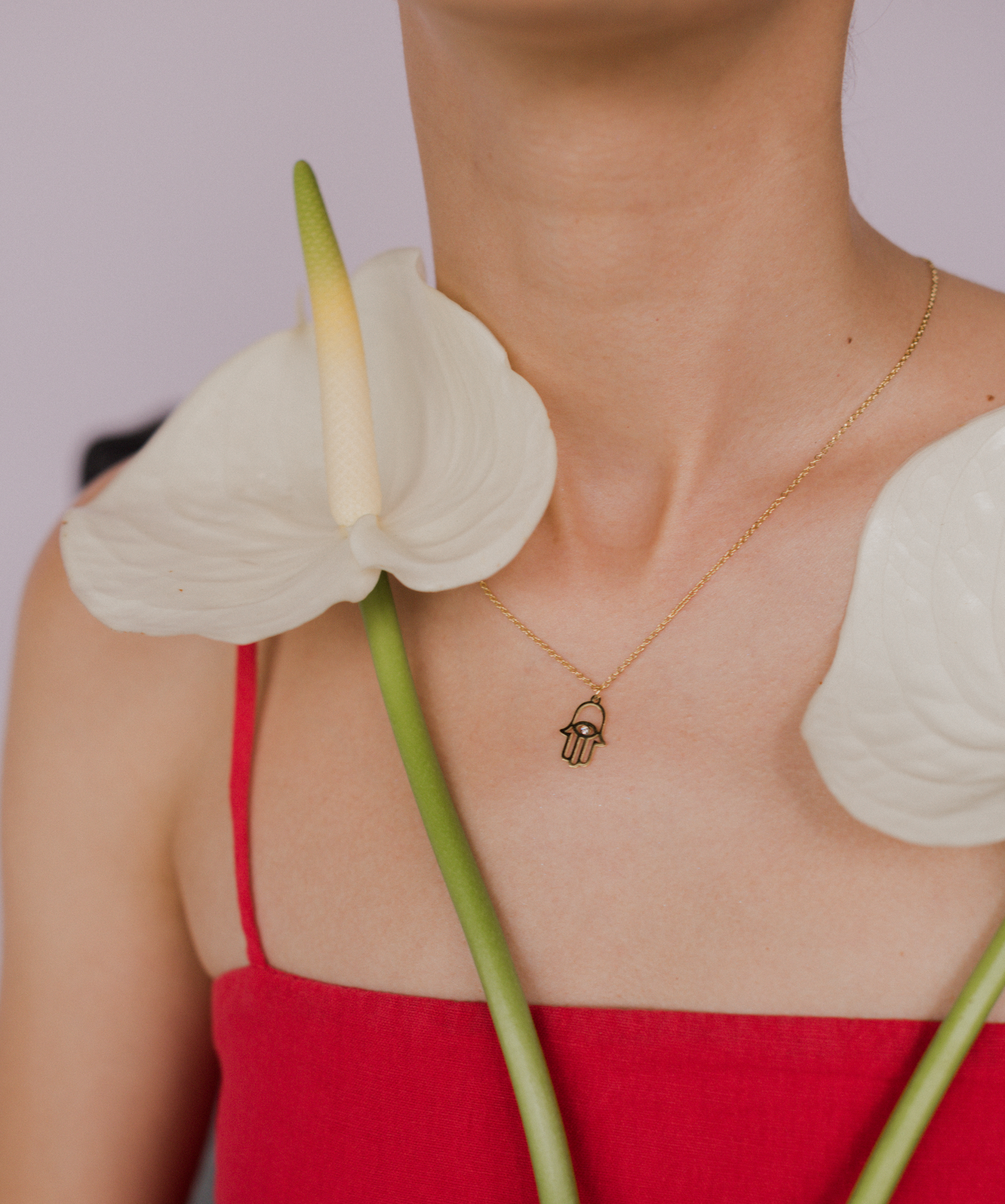 Dame hält zwei weiße Blumen und trägt vergoldete Kette mit Buddha Hand Anhänger