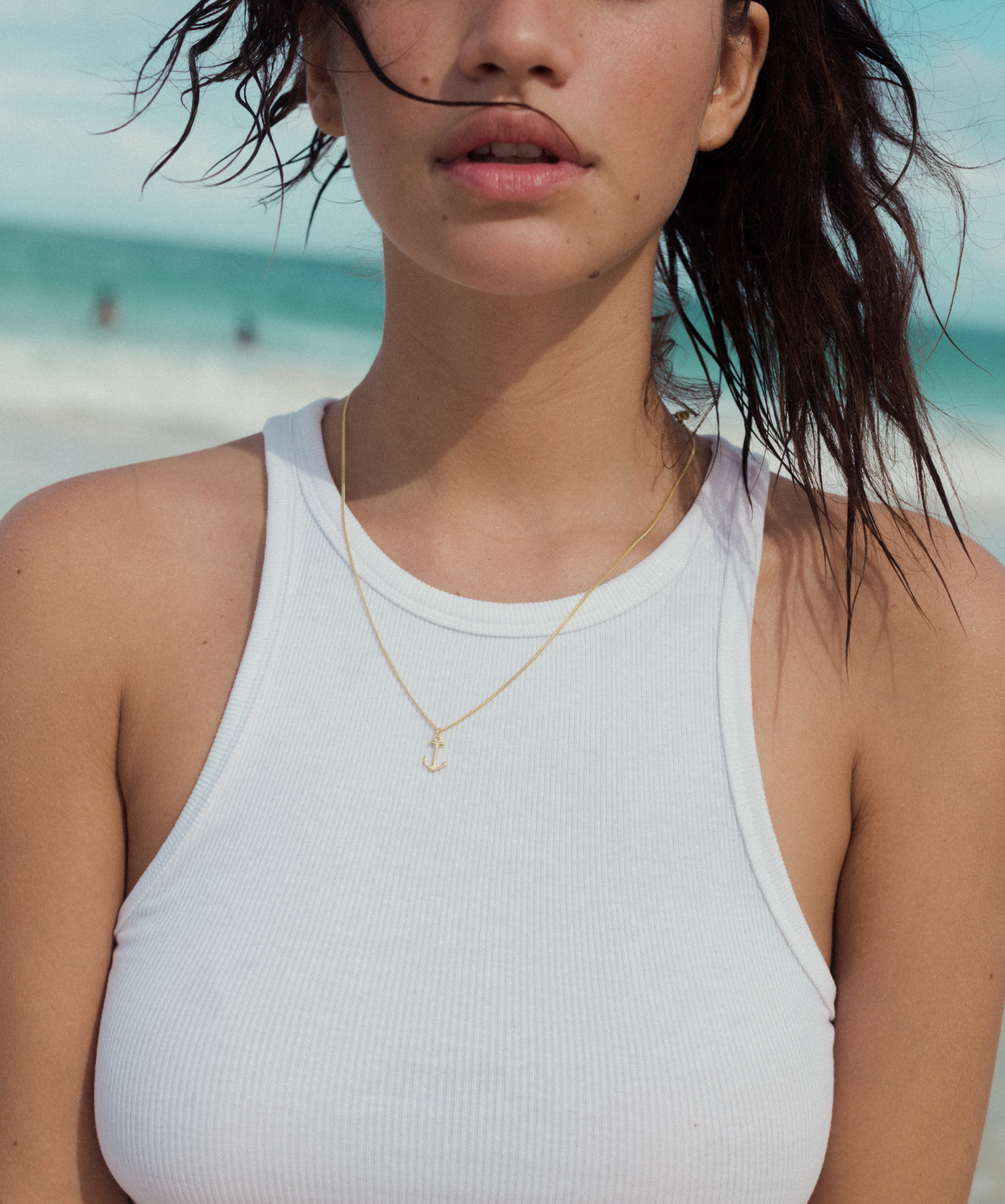 Mädchen am Strand trägt zarte Anker Anhänger Halskette in Gold 