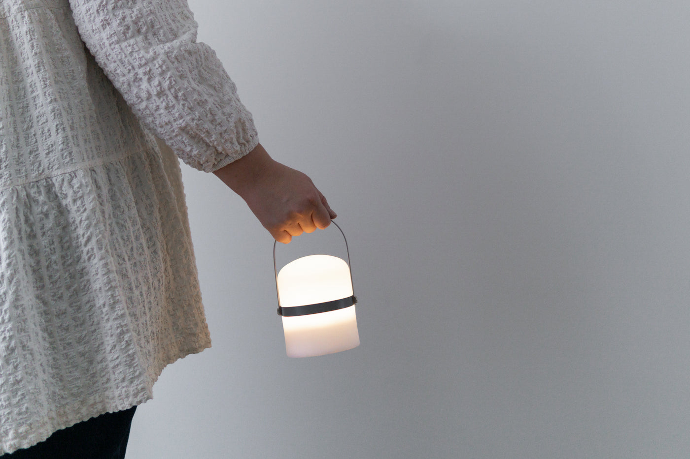 Frau hält moderne kleine LED Laterne am grauen Holz Griff 