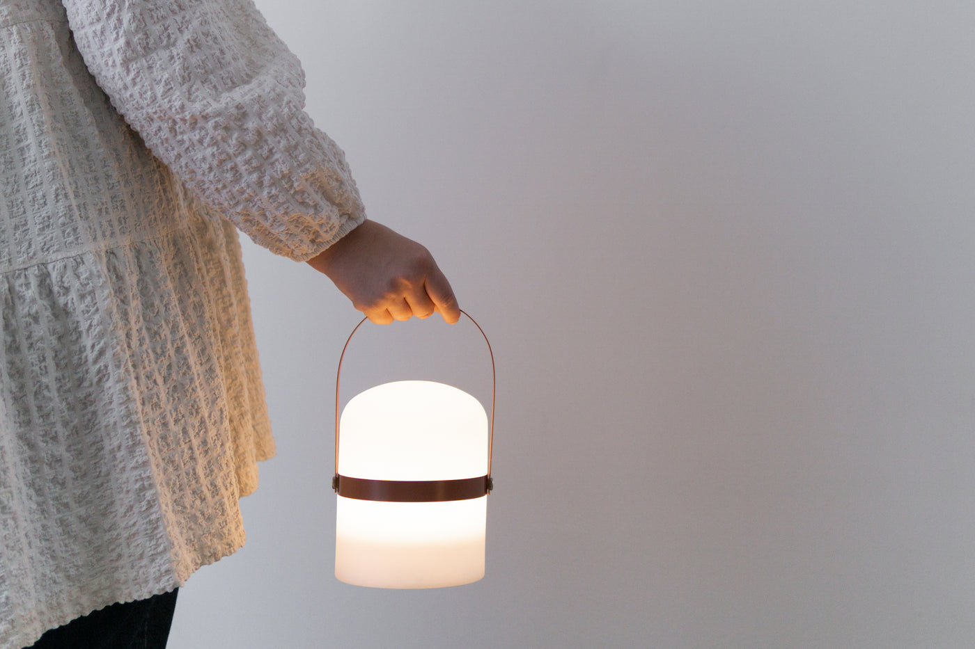 Frau hält moderne LED Laterne am Holz Griff in Terrakotta