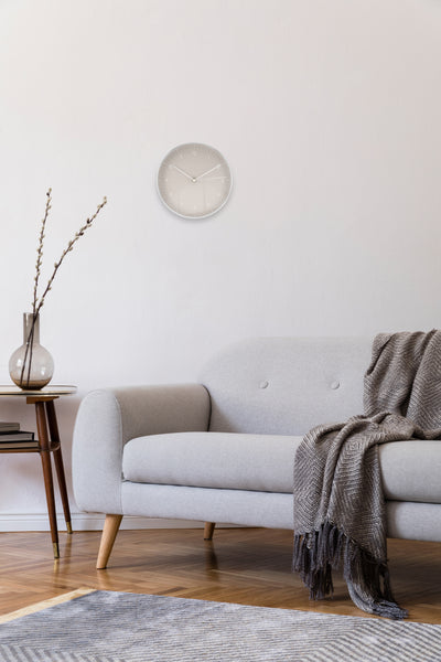 Gemütliches Wohnzimmer mit hellgrauer Wanduhr im Modernen Stil über Couch und Beistelltisch mit Vase