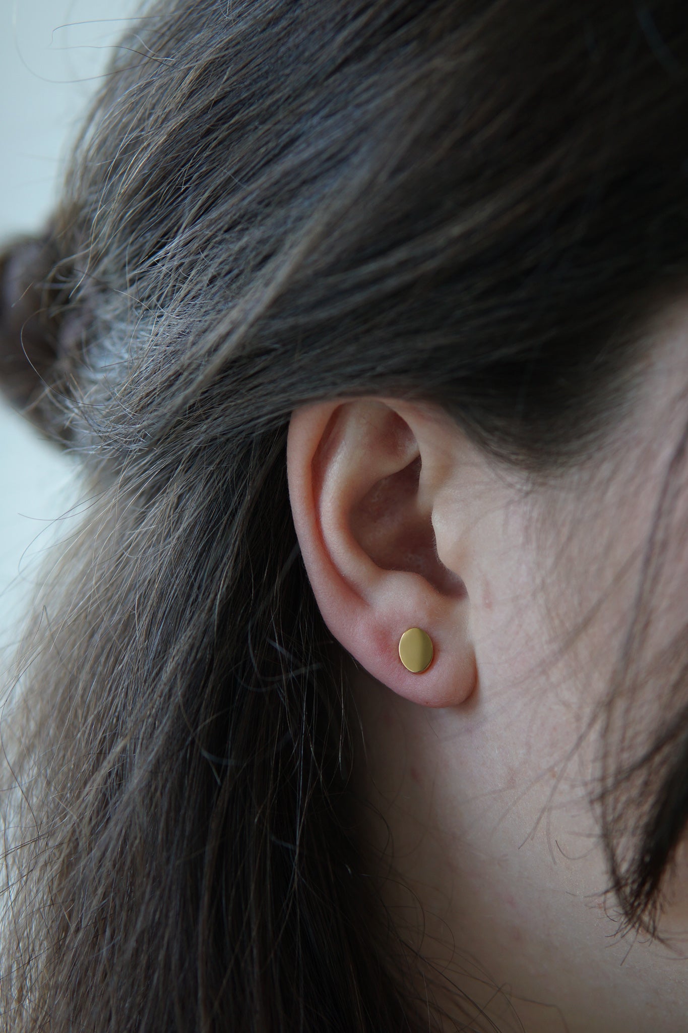 Junge Dame trägt Ohrringe mit Plättchen Stecker in Gold