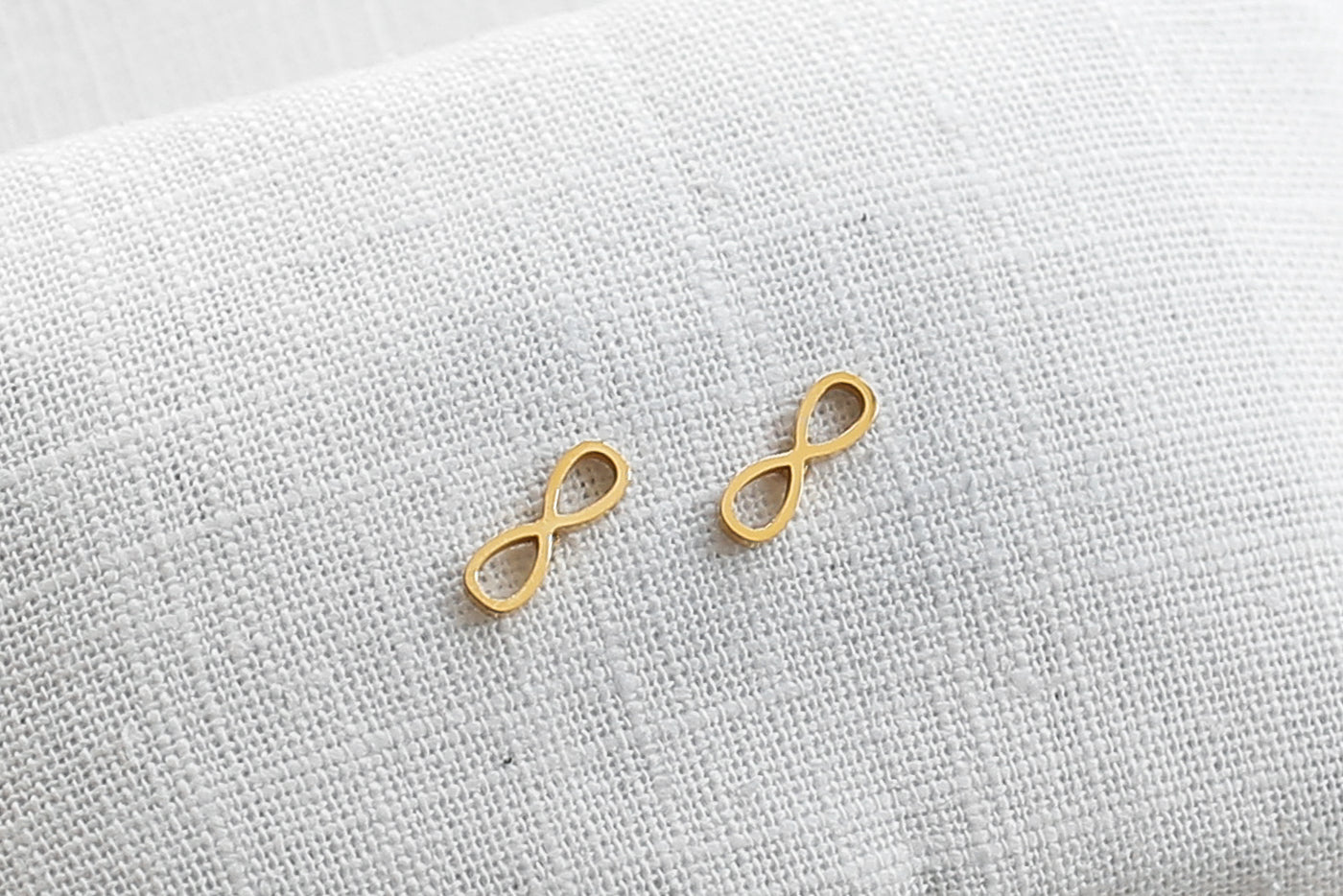 Infinity Ohrringe in Gold aus Edelstahl auf Stoff