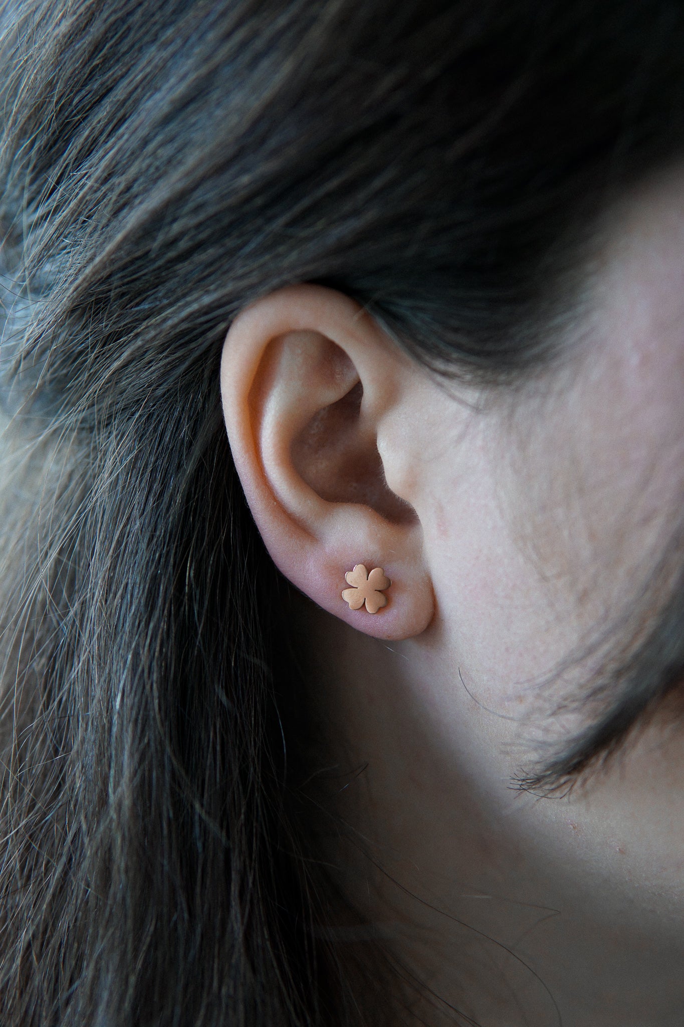 Junge Dame trägt goldene Ohrringe mit Kleeblatt Symbol