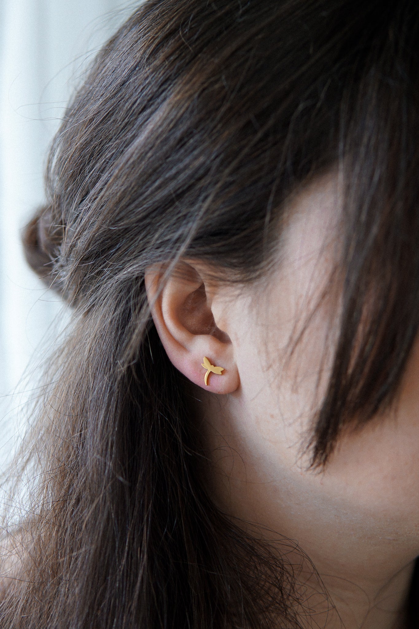 Juneg Frau trägt Libellen Ohrstecker in Gold für den edlen Look 
