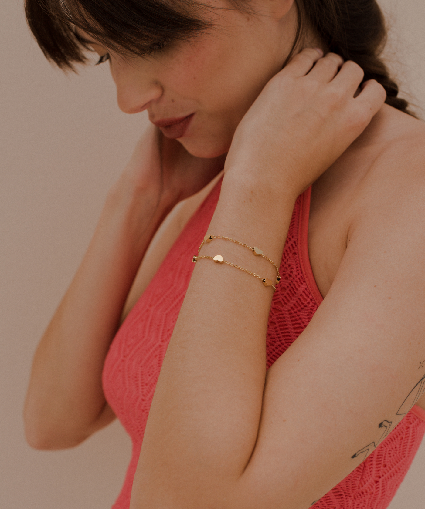 Frau trägt feminines Armband aus Gold mit vier Herz Anhängern