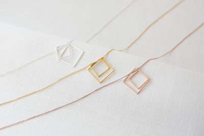 Sterling Silberne, Goldene und Rosegoldene Halsketten mit geometrischen Anhängern auf Leinen