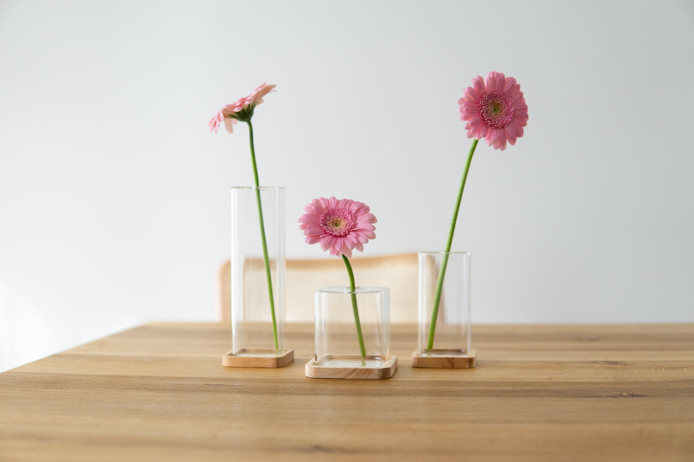 Quadratische Vasen mit Holzuntersetzern auf Esstisch