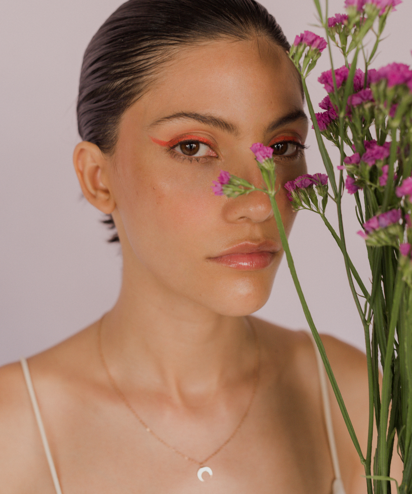 Junge Dame hält Blumen und trägt rose farbene Kette mit halb Mond Anhänger 